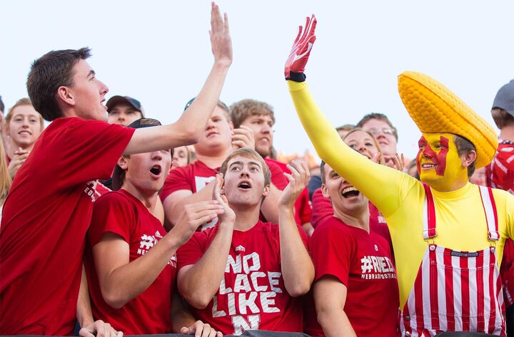 Fans high-fiving each other in stands of football game